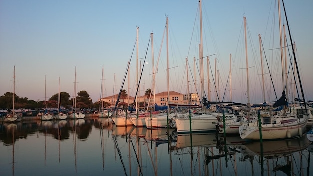 Boats moored at harbor against sky during sunset