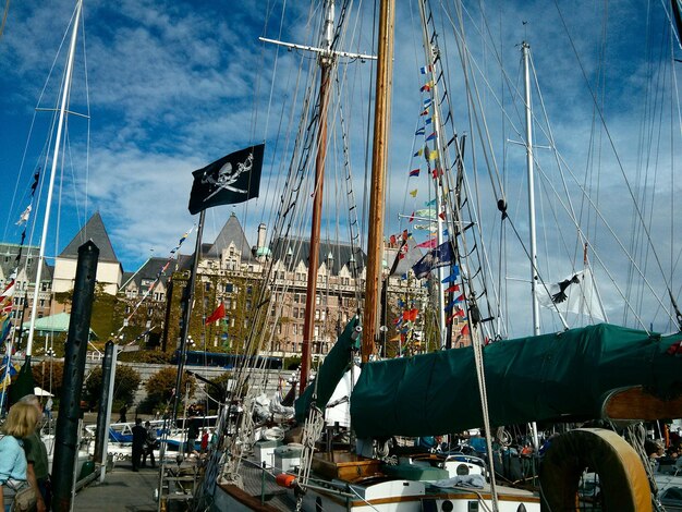 Boats moored at harbor by buildings against sky