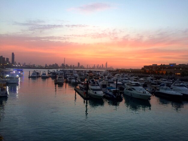 Boats moored at harbor during sunset