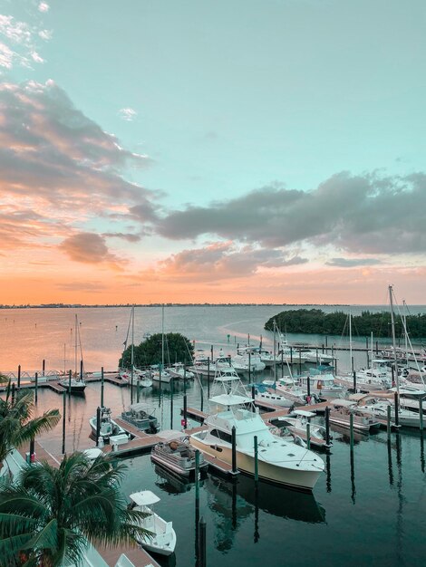 Boats moored in harbor at sunset