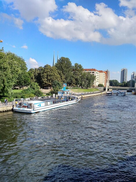 Boats moored on river in city against sky