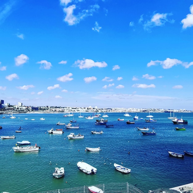 Boats moored in sea against blue sky