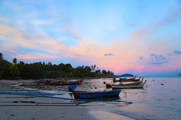 Boats moored on sea against sky during sunset