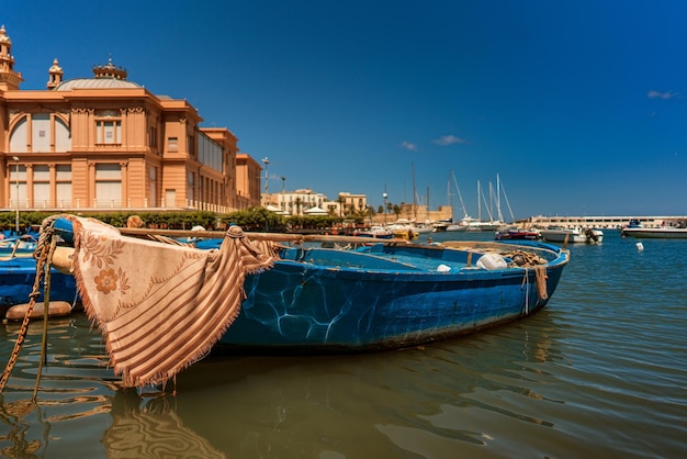 boats moored on sea by buildings against blue sky