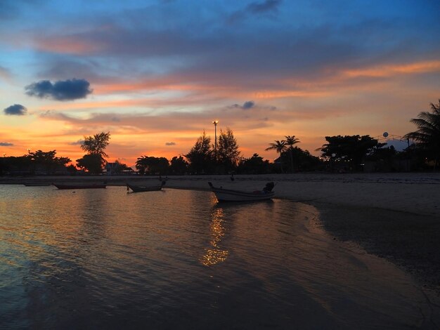 Foto barche ormeggiate sulla riva della spiaggia contro il cielo durante il tramonto