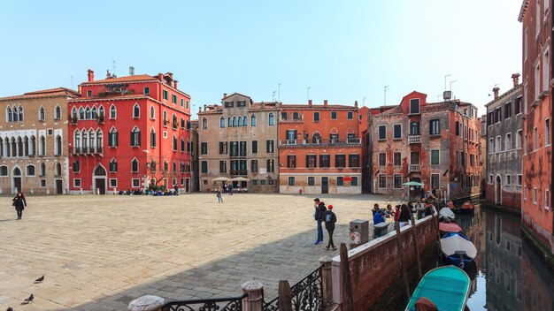 Boats on narrow canal between colorful historic houses in Venice.