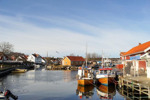 Boats in river by cityscape against sky