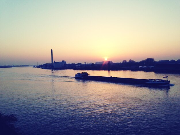 Foto barche che navigano sul fiume contro un cielo limpido durante il tramonto