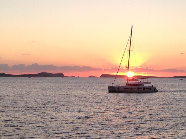 Boats sailing in sea against clear sky during sunset