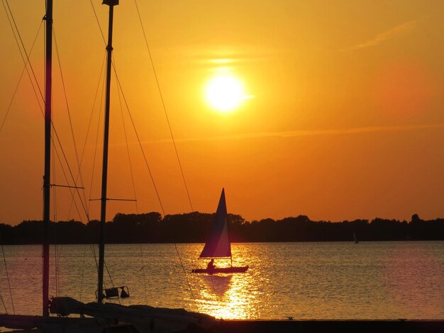 Boats sailing in sea at sunset