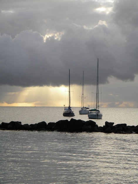 boats on sea against cloudy sky during sunset