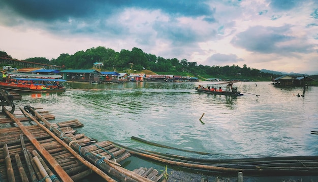 Boats in sea against cloudy sky