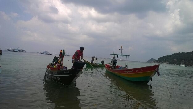 Boats in sea against cloudy sky