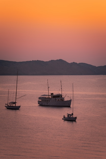 Boats seeing the sunset at August in Cavalleria beach at the north coast of Menorca, Spain. 