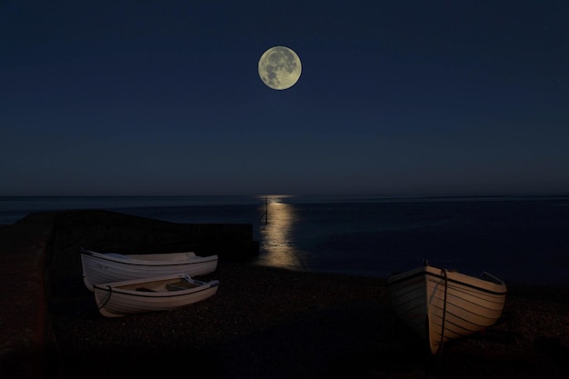 Boats on shore against the moon