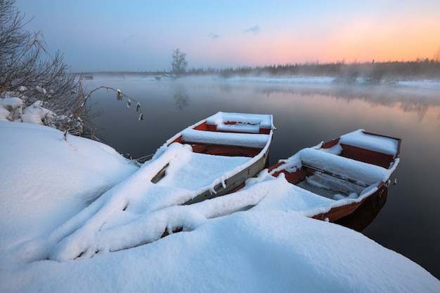 Photo boats in snow at the river in the winter