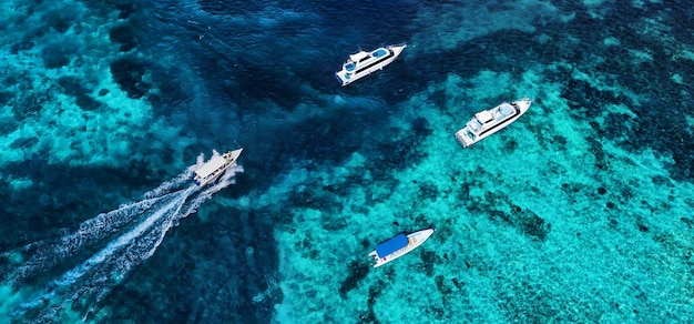 上から見た水面のボート ドローンから見た紺碧の水の背景 空から見た夏の海 旅行イメージ