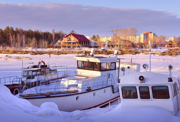 Boats and yachts in winter river boats spend the winter on the shore among snowdrifts