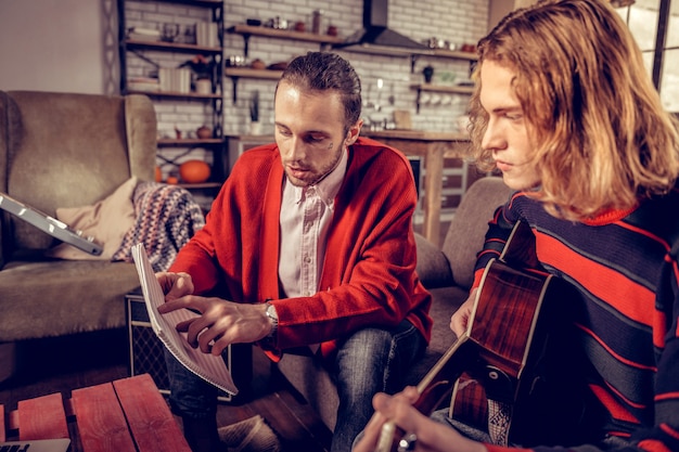 Bob cut. Blonde-haired talented hard-working musician with bob cut listening to his colleague