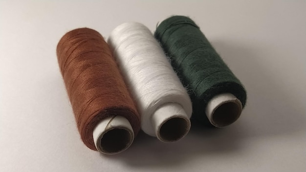 Bobbins and spools of thread of different colors brown white and green Closeup Natural light on the left side Skeins of thread Sewing supplies