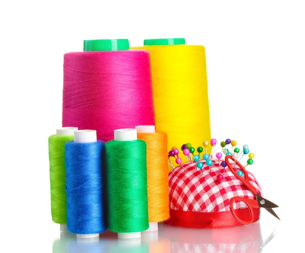 Bobbins of thread with colored pinheads in pincushion isolated on white