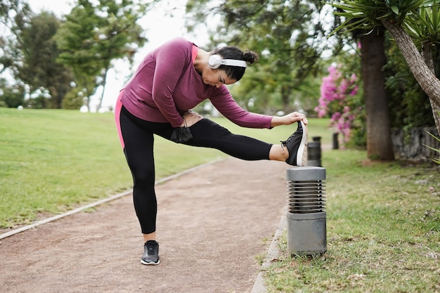 Bochtige vrouw doet stretchin sporttraining in het stadspark terwijl ze een veiligheidsmasker op haar arm draagt voor een uitbraak van het coronavirus