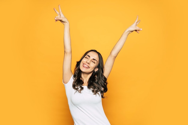 Bodacious awake girl with her hands up showing ã¢ââpeaceã¢ââ sign, wide smile and the tongue out of the mouth which tells about her happy mood