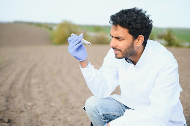 Bodemonderzoek Indiase agronomiespecialist die bodemmonsters neemt voor vruchtbaarheidsanalyse Handschoenen in close-up Milieubescherming biologische bodemcertificering veldwerkonderzoek