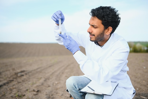 Bodemonderzoek Indiase agronomiespecialist die bodemmonsters neemt voor vruchtbaarheidsanalyse Handschoenen in close-up Milieubescherming biologische bodemcertificering veldwerkonderzoek