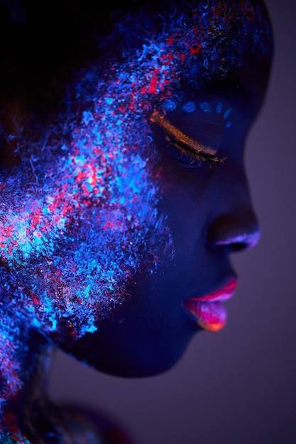 Body art che emette luce ultravioletta, viso ravvicinato di una donna nera con grandi labbra