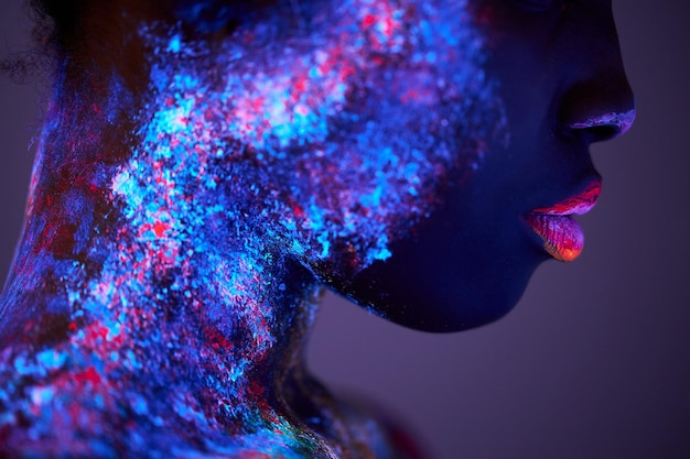 Body art glowing in ultraviolet light closeup face of black\
woman with big lips