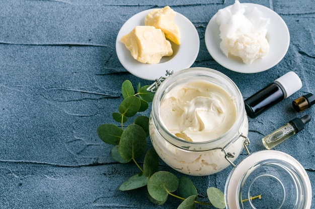 body butter met ingrediënten en etherische olie op een donkere betonnen ondergrond