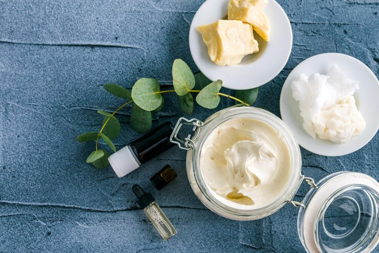 body butter with ingredients and essential oil on a dark concrete background