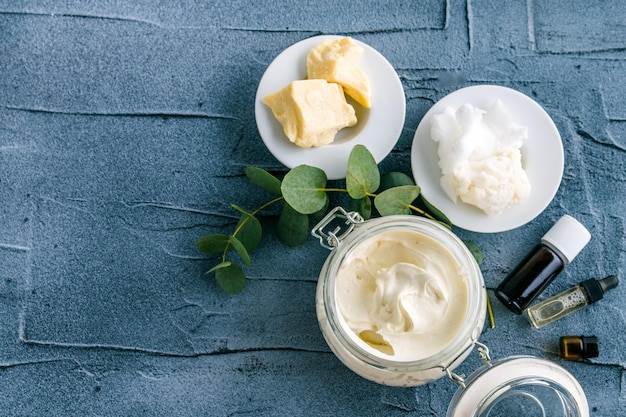 body butter with ingredients and essential oil on a dark concrete background