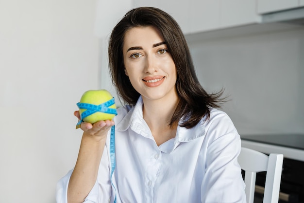 Body care Cropped image of a nutritionist woman wrapped an apple a measuring tape