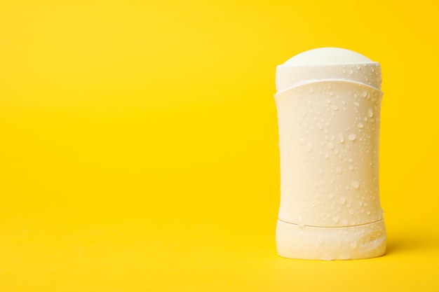 Body deodorant on yellow background, blank space for text
