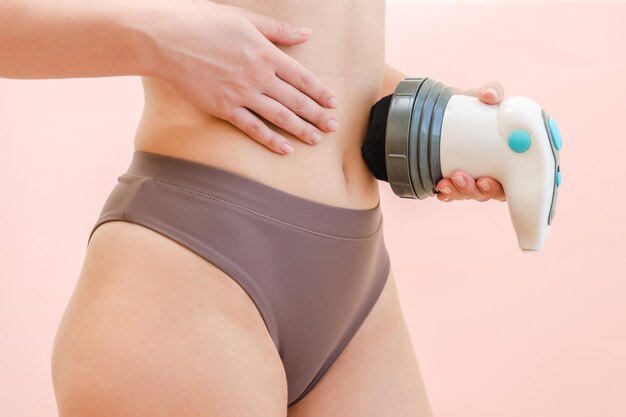 Body massager on female stomach with pink background