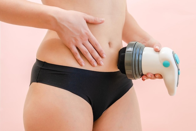 Body massager on female stomach with pink background