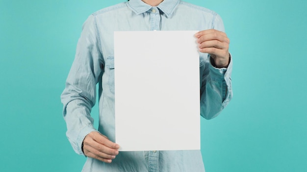 The body part of a woman and two hands holding a white sheet a4 board on a green mint backgroundVertical line