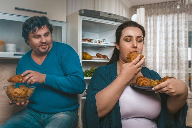 Coppie positive del corpo che mangiano troppo cibo non sano prima di coricarsi