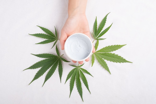 Body scrub in hand with cannabis leaves