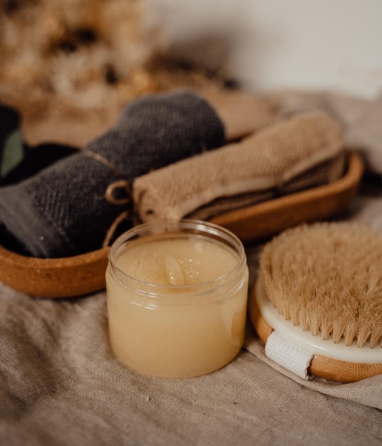 Photo body scrub in plastic jar beside body brush