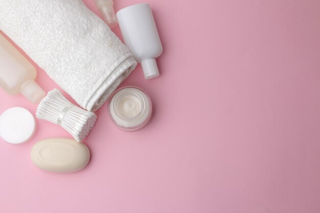 Body and skin care products in white packaging on a pink table