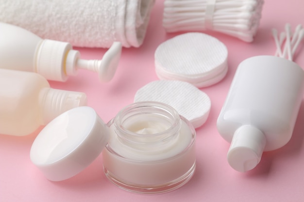 Body and skin care products in white packaging on a pink table