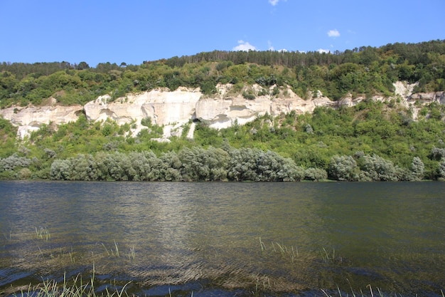 A body of water with a cliff and trees