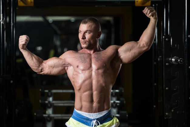 Bodybuilder die biceps poseert na oefeningen