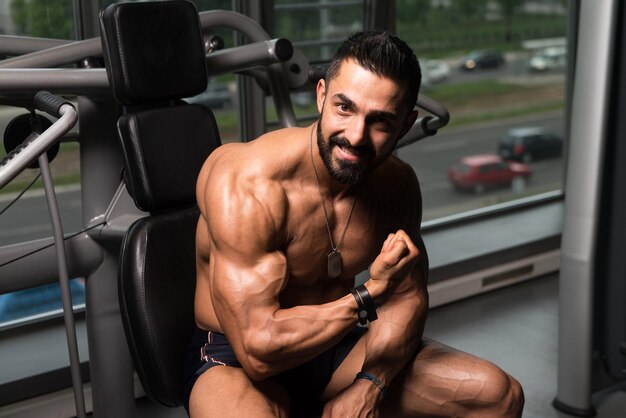 Bodybuilder die biceps poseert na oefeningen