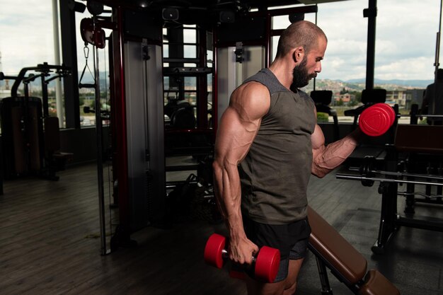 Bodybuilder die biceps traint met halters