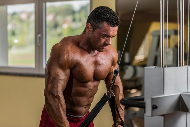 bodybuilder doet zware oefening voor triceps met kabel