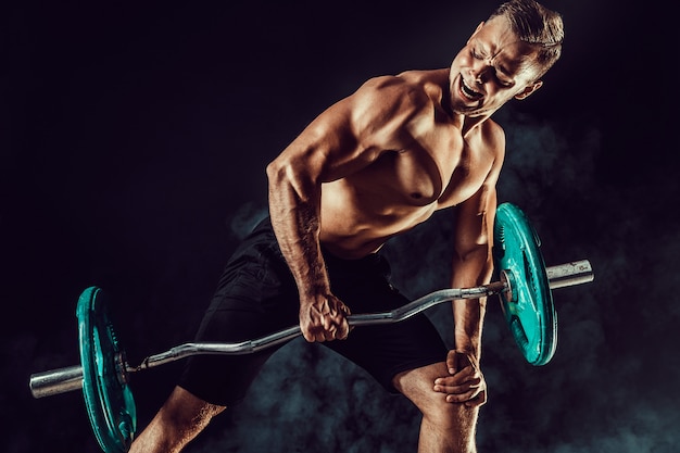 Photo bodybuilder doing exercise for muscles of back with a barbell